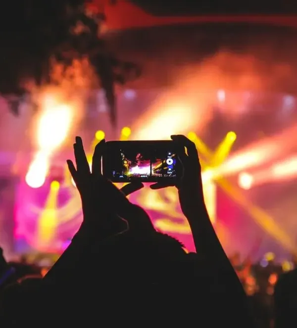 silhouette-of-a-fan-in-crowded-audience-filming-live-concert-bright-lights
